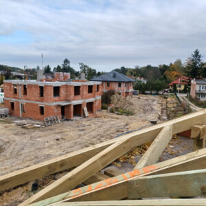 Widok na dom K z ukończonymi oboma piętrami i dom L z dachem i oknami