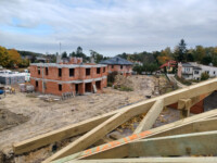 Widok na dom K z ukończonymi oboma piętrami i dom L z dachem i oknami